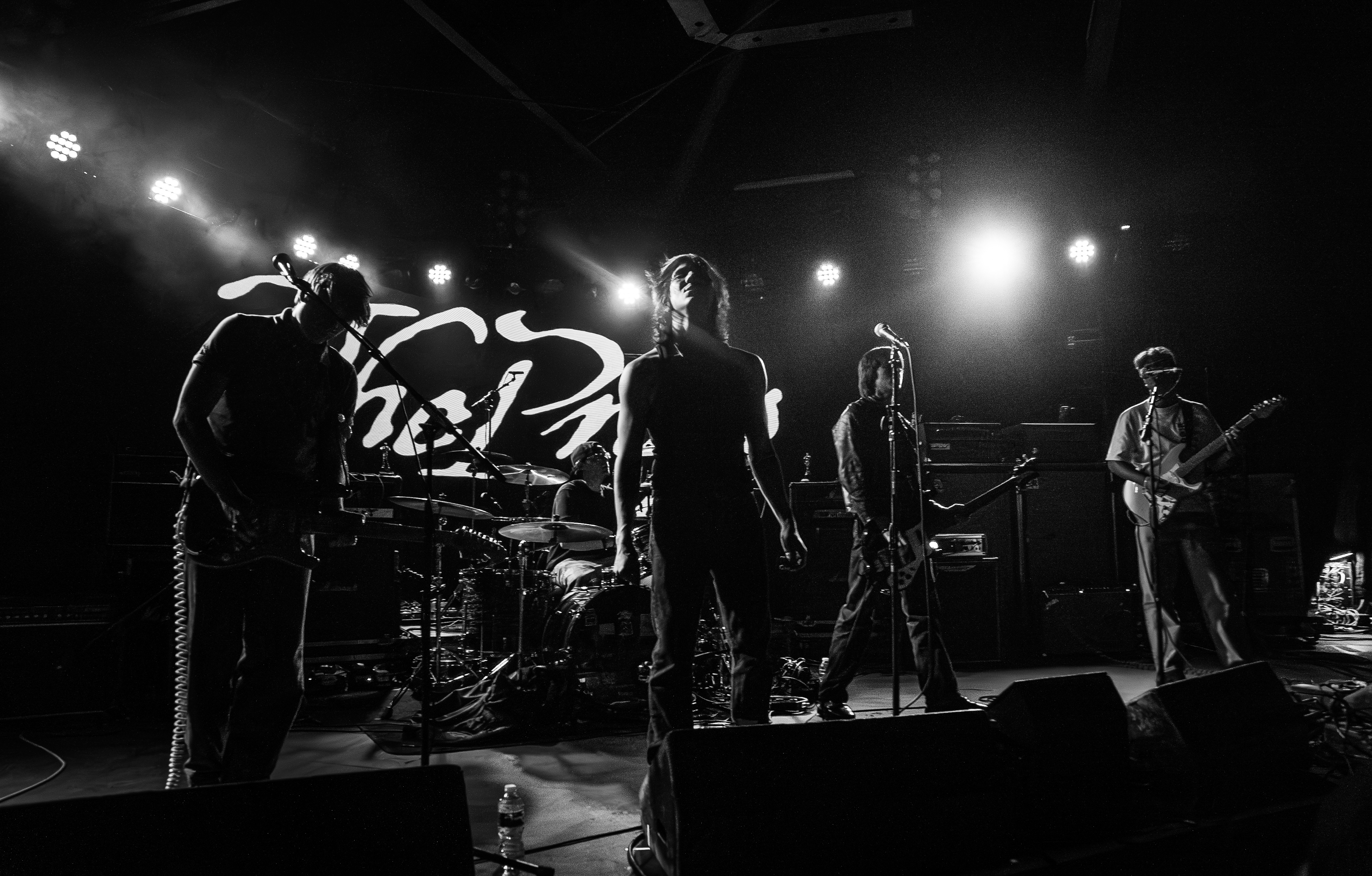 The Props performing live on stage under bright lights, shot in black and white